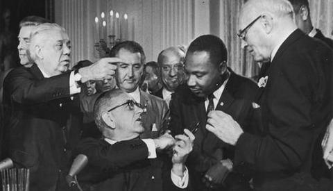 Lyndon Johnson总统在签署1964年的民权法案时震撼马丁路德王博士的手。